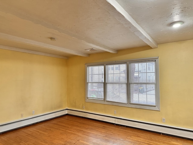 unfurnished room featuring beamed ceiling, baseboard heating, hardwood / wood-style floors, and plenty of natural light