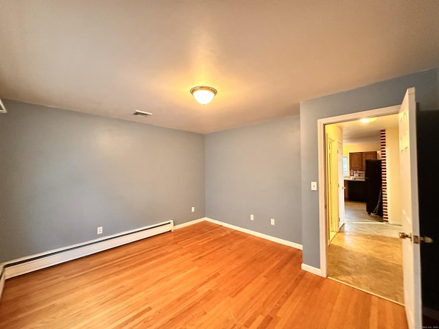 empty room featuring a baseboard heating unit and light hardwood / wood-style floors