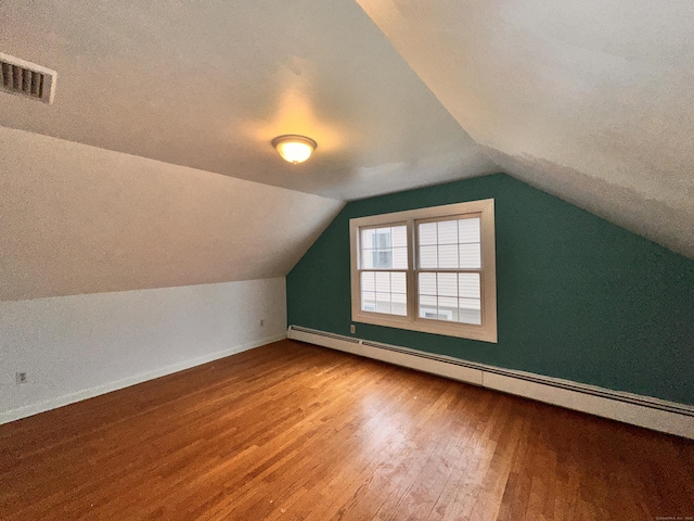 additional living space featuring lofted ceiling, hardwood / wood-style floors, and baseboard heating