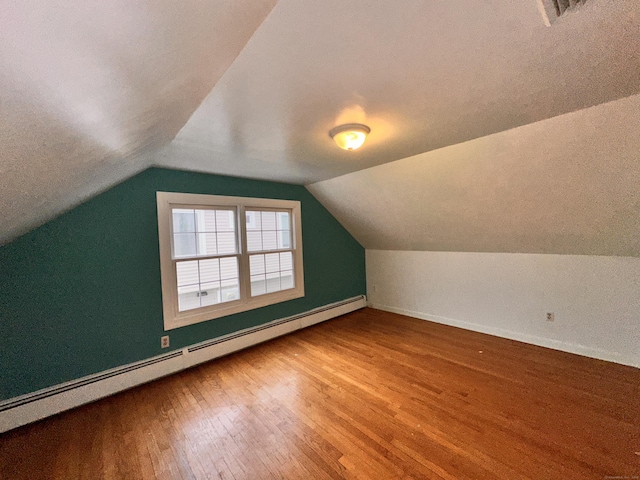 additional living space featuring baseboard heating, lofted ceiling, and hardwood / wood-style flooring