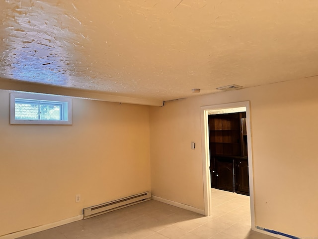 unfurnished room featuring a baseboard heating unit and a textured ceiling