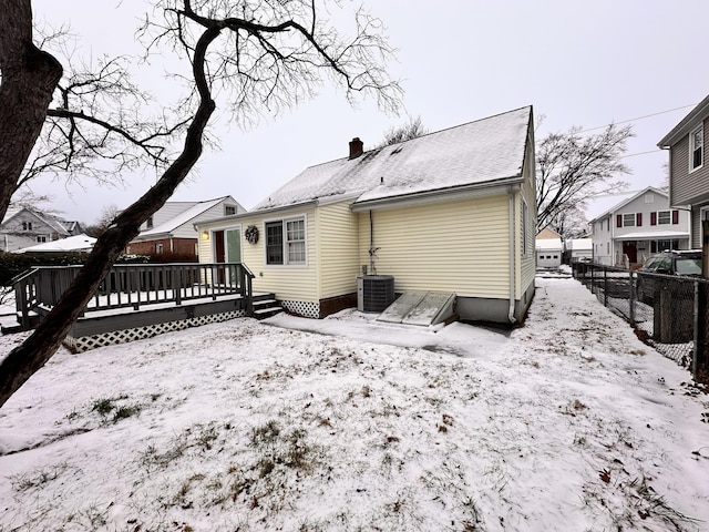 snow covered house featuring a wooden deck and central air condition unit