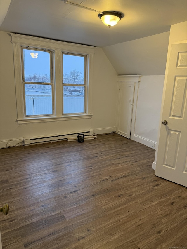 additional living space with lofted ceiling, dark hardwood / wood-style floors, and a baseboard heating unit