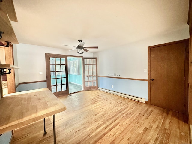 interior space featuring baseboard heating, ceiling fan, light hardwood / wood-style floors, and french doors