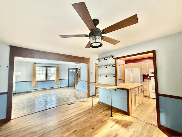 interior space with butcher block counters, light wood-type flooring, baseboard heating, a kitchen island, and white appliances