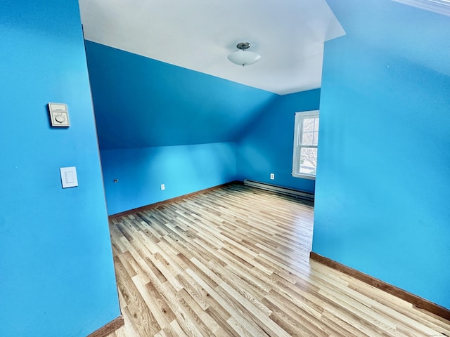 additional living space with lofted ceiling, baseboard heating, and light hardwood / wood-style flooring