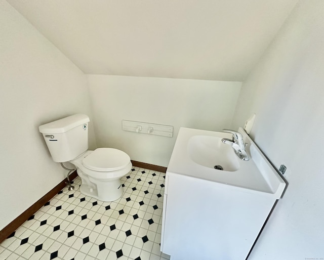 bathroom featuring vanity, toilet, and vaulted ceiling