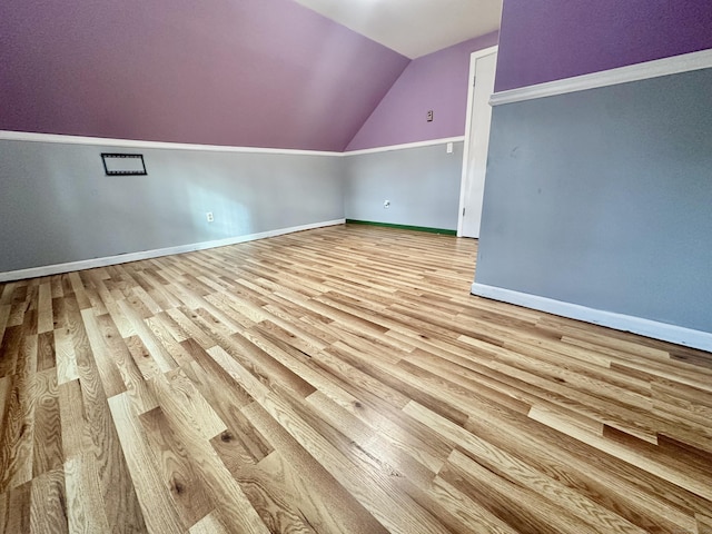 additional living space featuring vaulted ceiling and light hardwood / wood-style flooring