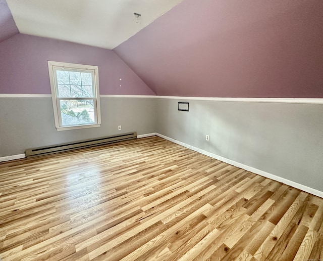 additional living space with a baseboard radiator, lofted ceiling, and light hardwood / wood-style floors