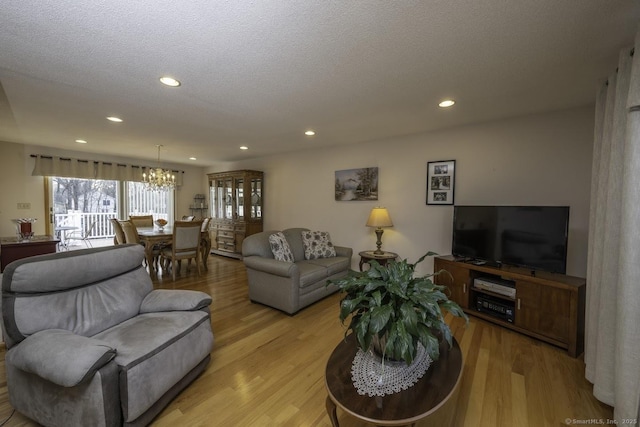 living room featuring a textured ceiling, an inviting chandelier, and light hardwood / wood-style flooring