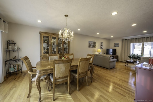 dining room with a chandelier, a textured ceiling, and light wood-type flooring