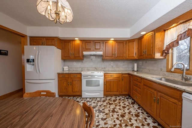 kitchen featuring sink, a chandelier, a textured ceiling, white appliances, and light stone countertops