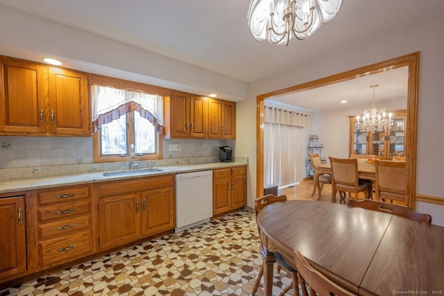 kitchen with sink, an inviting chandelier, white dishwasher, tasteful backsplash, and decorative light fixtures