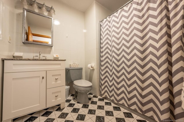 bathroom with tile patterned floors, toilet, tile walls, vanity, and a shower with shower curtain