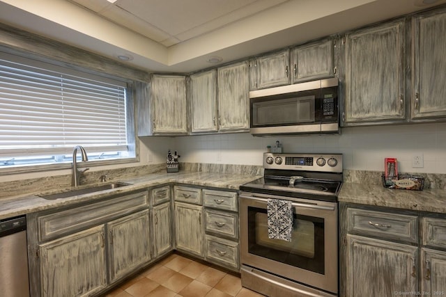 kitchen featuring stainless steel appliances, light stone countertops, sink, and decorative backsplash