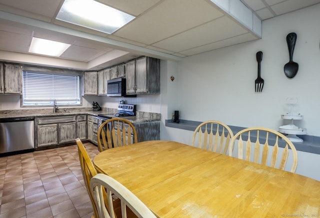 kitchen featuring a drop ceiling, sink, light tile patterned flooring, and appliances with stainless steel finishes