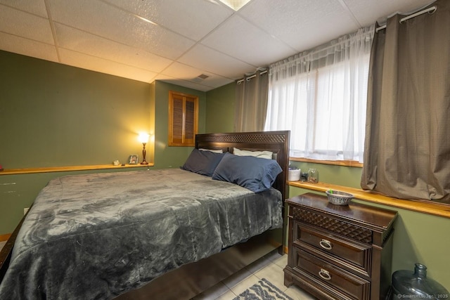 bedroom with light tile patterned flooring and a drop ceiling