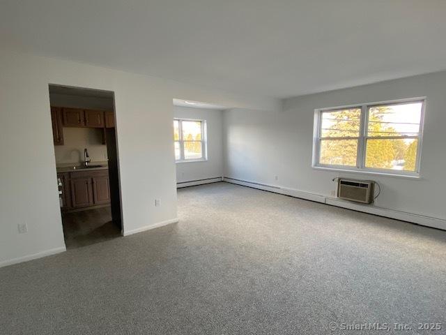 carpeted empty room featuring sink and a wall unit AC