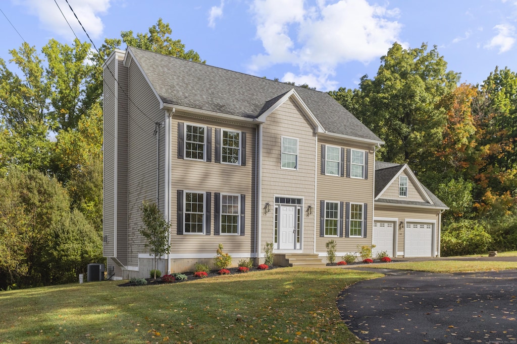 colonial house featuring a garage and a front lawn