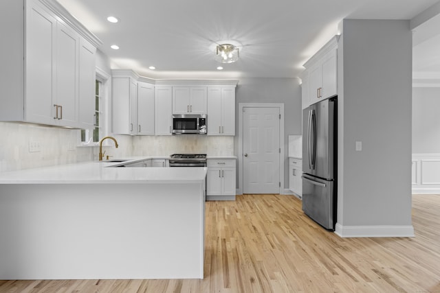 kitchen with white cabinetry, sink, backsplash, light hardwood / wood-style floors, and stainless steel appliances