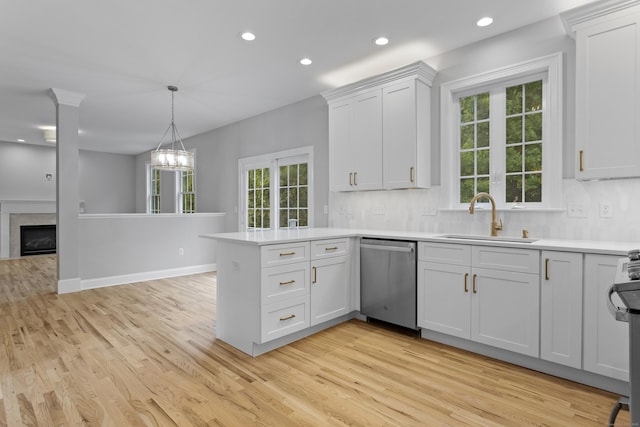 kitchen featuring tasteful backsplash, dishwasher, sink, white cabinets, and kitchen peninsula