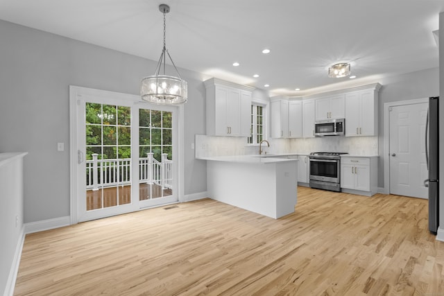 kitchen with appliances with stainless steel finishes, kitchen peninsula, and white cabinets