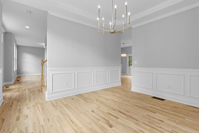 unfurnished room with crown molding, a notable chandelier, and light hardwood / wood-style floors