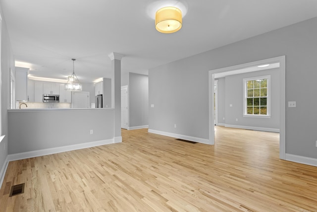 unfurnished living room with a chandelier and light hardwood / wood-style floors