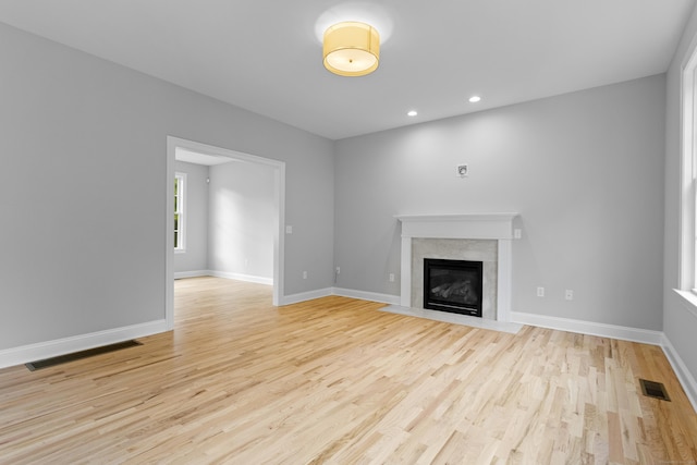 unfurnished living room featuring a fireplace and light hardwood / wood-style floors