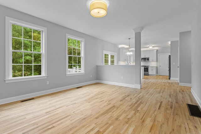 unfurnished living room featuring a chandelier and light hardwood / wood-style floors