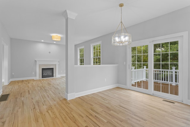 unfurnished dining area featuring an inviting chandelier and light hardwood / wood-style flooring