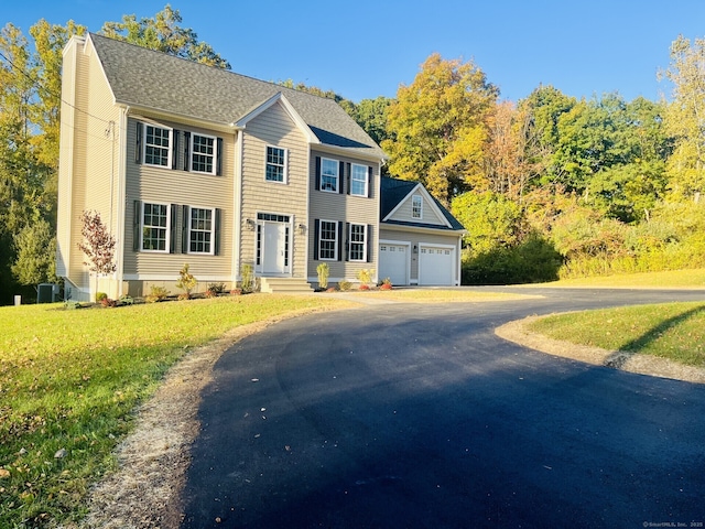 colonial inspired home with a garage and a front yard