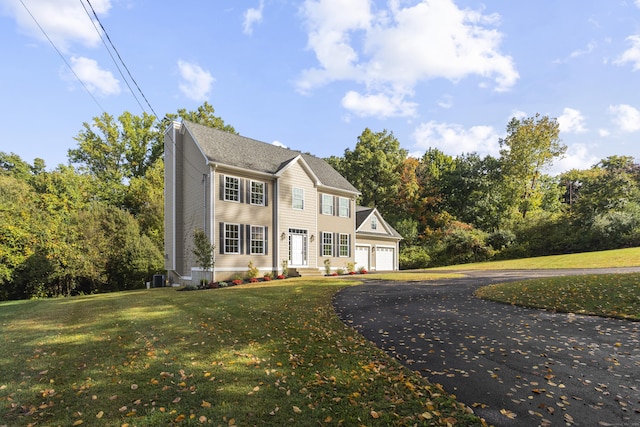 colonial inspired home featuring a garage, central AC unit, and a front yard