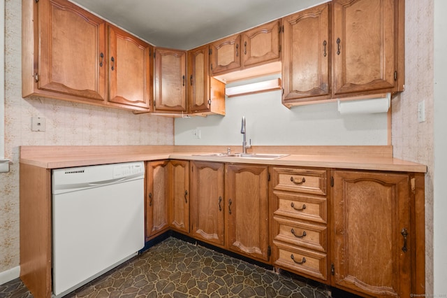 kitchen with brown cabinetry, light countertops, dishwasher, and a sink