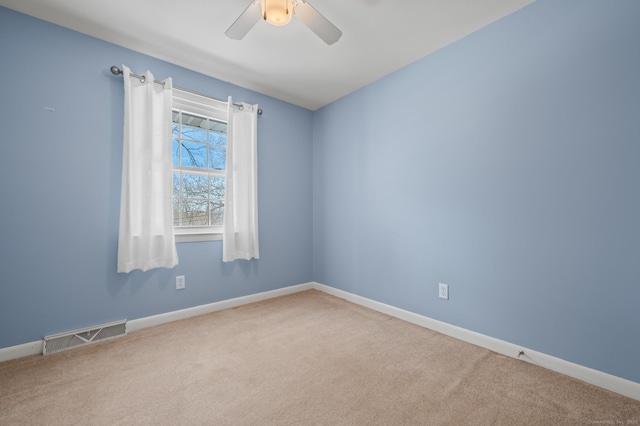 carpeted empty room featuring a ceiling fan, visible vents, and baseboards