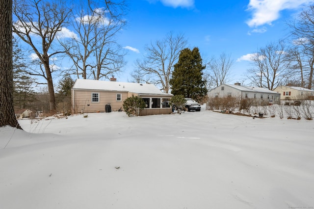 snow covered rear of property featuring a chimney