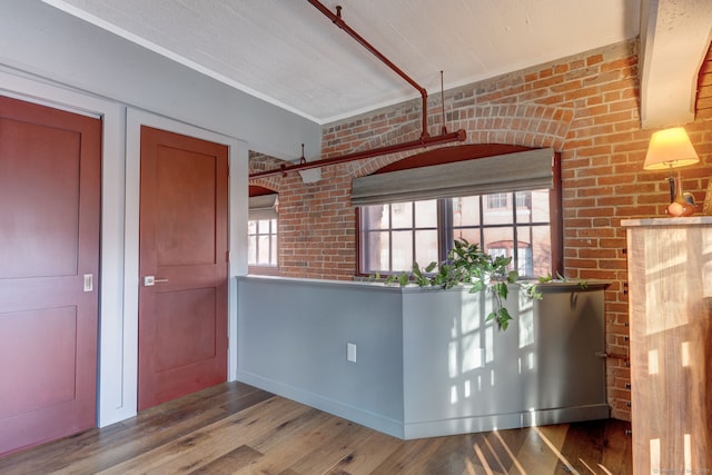 kitchen featuring brick wall and wood-type flooring