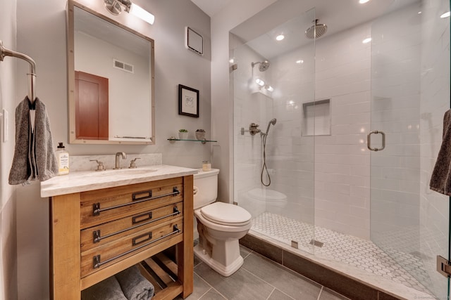 bathroom with tile patterned floors, toilet, a shower with shower door, and vanity