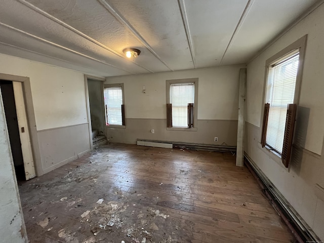 unfurnished room with dark hardwood / wood-style flooring and a baseboard heating unit