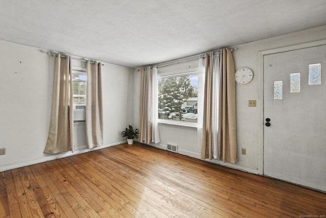 unfurnished room featuring wood-type flooring and visible vents