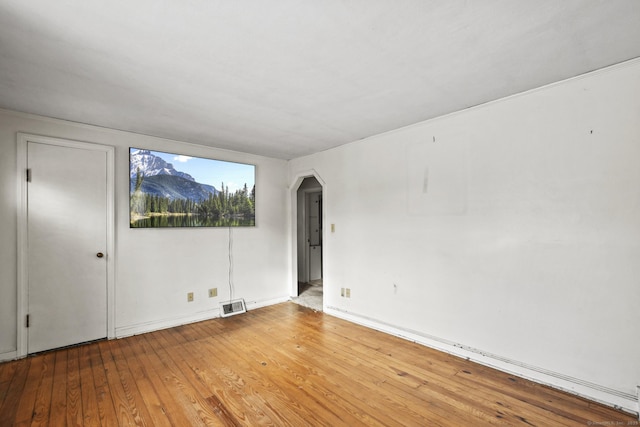 spare room featuring arched walkways, visible vents, and hardwood / wood-style flooring