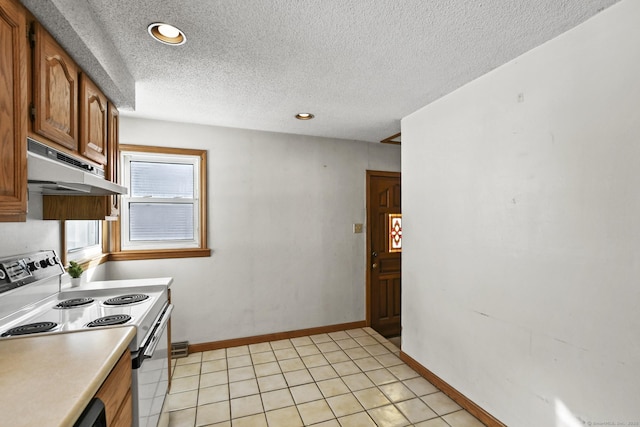 kitchen featuring white range with electric cooktop, light countertops, brown cabinetry, under cabinet range hood, and baseboards