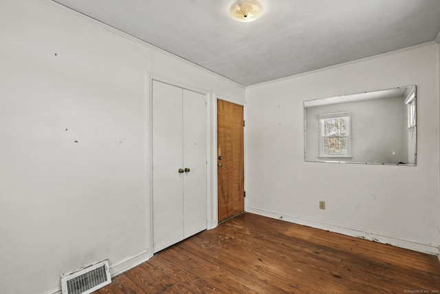 unfurnished bedroom with a closet, visible vents, and wood finished floors