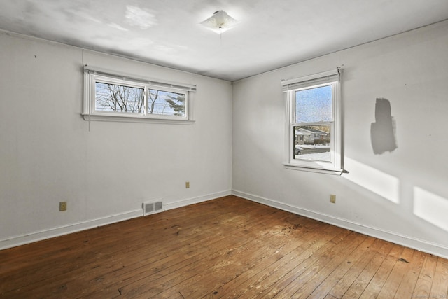 unfurnished room with visible vents, hardwood / wood-style flooring, and baseboards