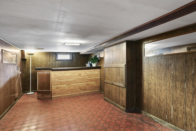 interior space with a bar, wooden walls, and dark floors