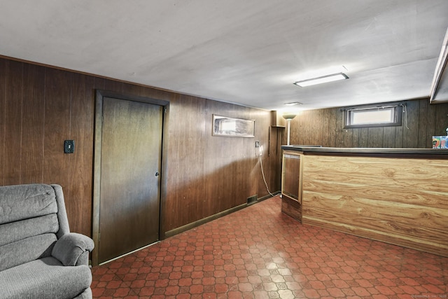 basement with dark floors, a dry bar, and wood walls