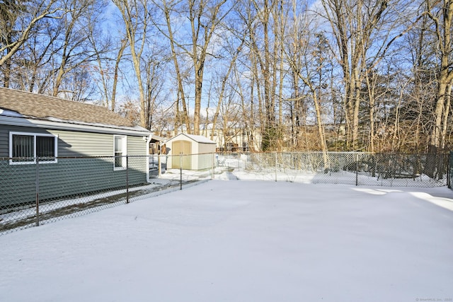 snowy yard featuring fence private yard, a storage unit, and an outbuilding