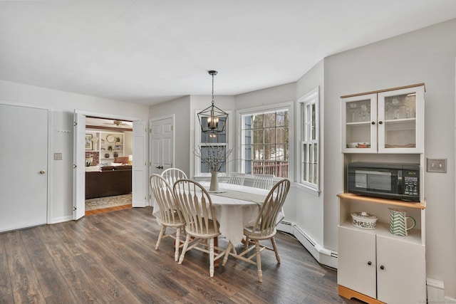 dining area featuring dark hardwood / wood-style flooring, a baseboard radiator, and an inviting chandelier