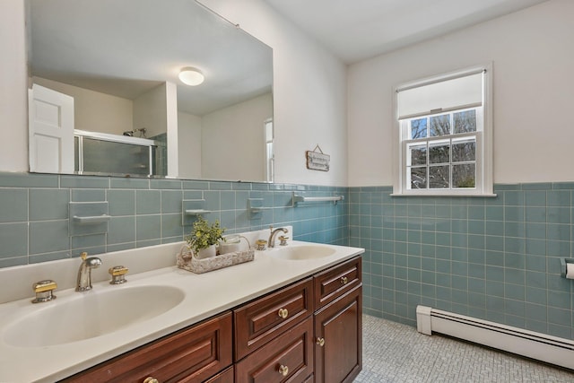 bathroom with tile walls, vanity, a shower with door, tile patterned flooring, and a baseboard heating unit