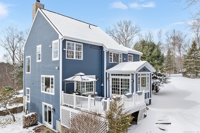 snow covered house with a wooden deck